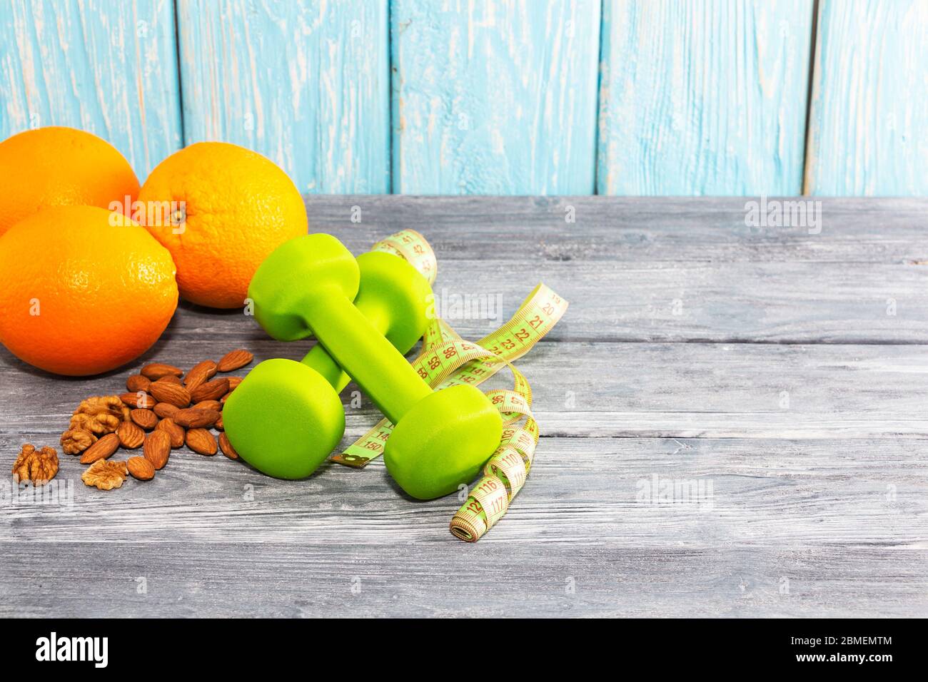 Viele Orangen, Hanteln, Maßband auf einem texturierten Holzhintergrund. Fitness, Sporternährung Stockfoto