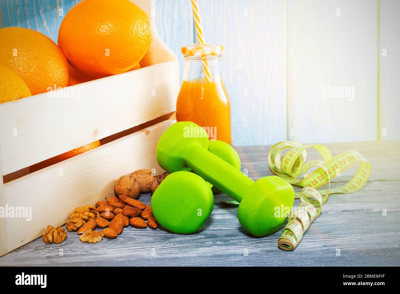 Viele Orangen, Hanteln, Maßband auf einem texturierten Holzhintergrund. Fitness, Sporternährung Stockfoto