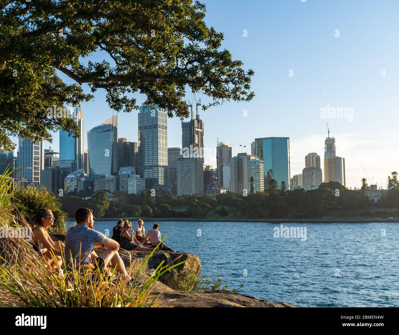 Eine Gruppe junger Leute, die den Sonnenuntergang am Lady Macquaire's Chair und Sydney genießen Stockfoto