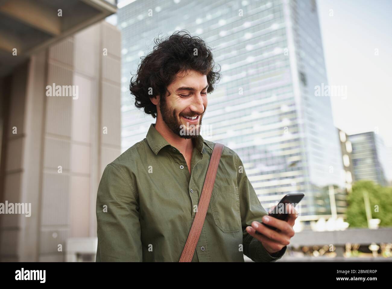 Schöner lächelnder junger Mann in formeller Kleidung mit Smartphone Stockfoto