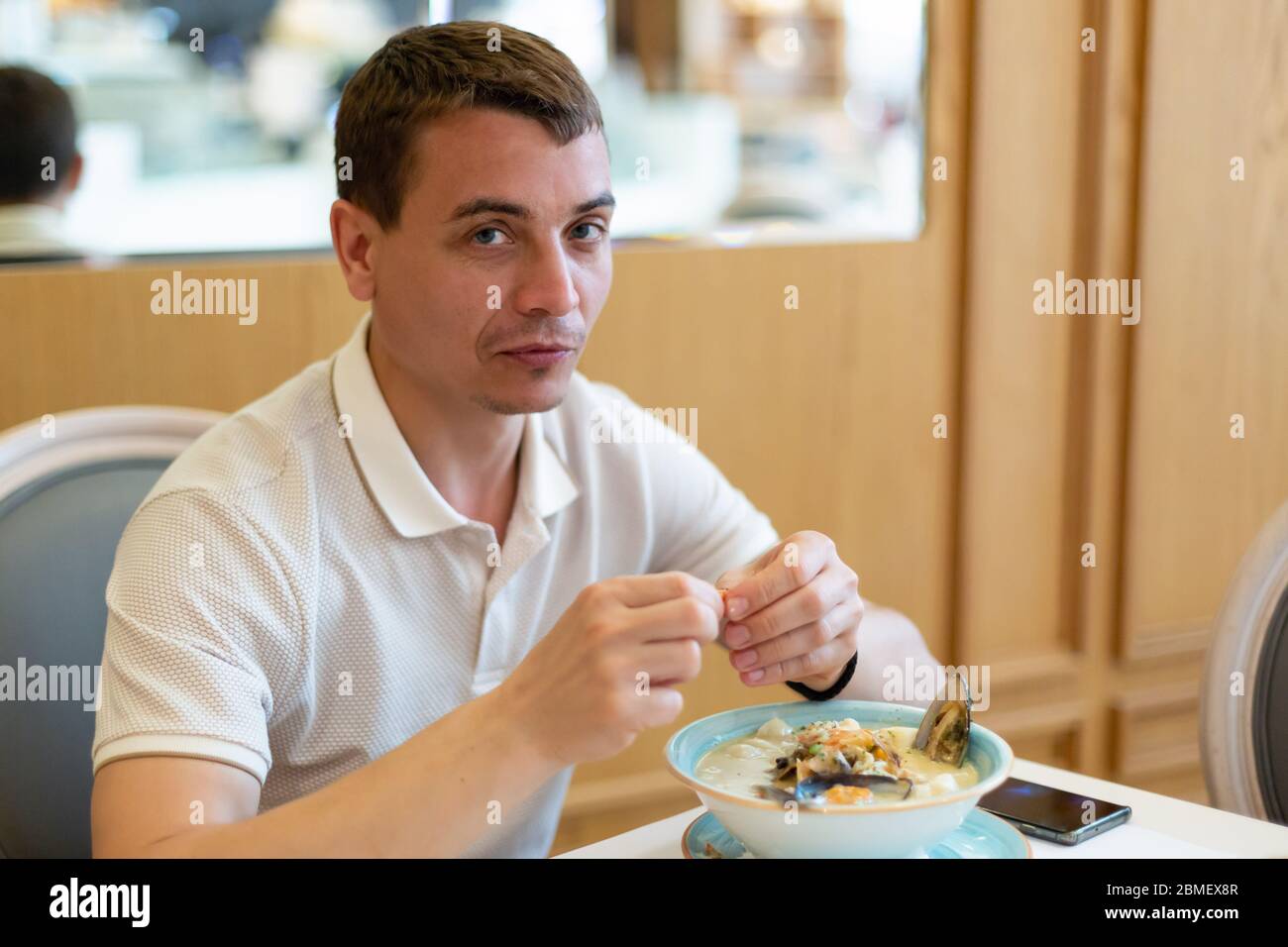 Ein erwachsener Europäer von 30-35 Jahren isst in einem Restaurant Meeresfrüchte-Suppe. Stockfoto