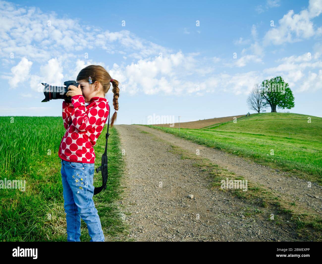 Junges Mädchen mit großer Kamera in der ländlichen Schweiz, das Bilder von der Landschaft. Stockfoto