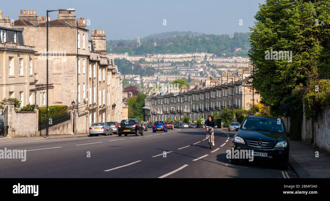 Bath, England, UK - 20. April 2011: Ein Radfahrer fährt auf dem steilen Bathwick Hill vorbei an den georgischen Häusern und dem Stadtbild von Bath in Somerset. Stockfoto