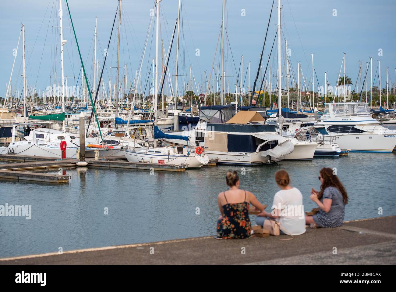 Menschen, die während der Coronavirus-Krise (COVID-19) vor Manly Marina sitzen.die Regierung von Queensland lockert die Sperrregeln. Freizeitaktivitäten und gesellschaftliche Treffen von 10 werden ab 16. Mai erlaubt sein. Stockfoto