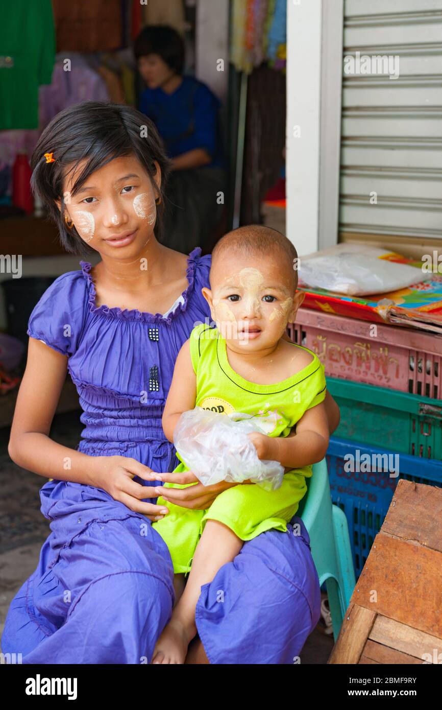 Yangon Myanmar - Oktober 26 2013; Myanmar Reisebilder Teenager-Mädchen und ihre kleine Schwester beide mit traditionellem Thanaka auf ihren Gesichtern sitzen in str Stockfoto