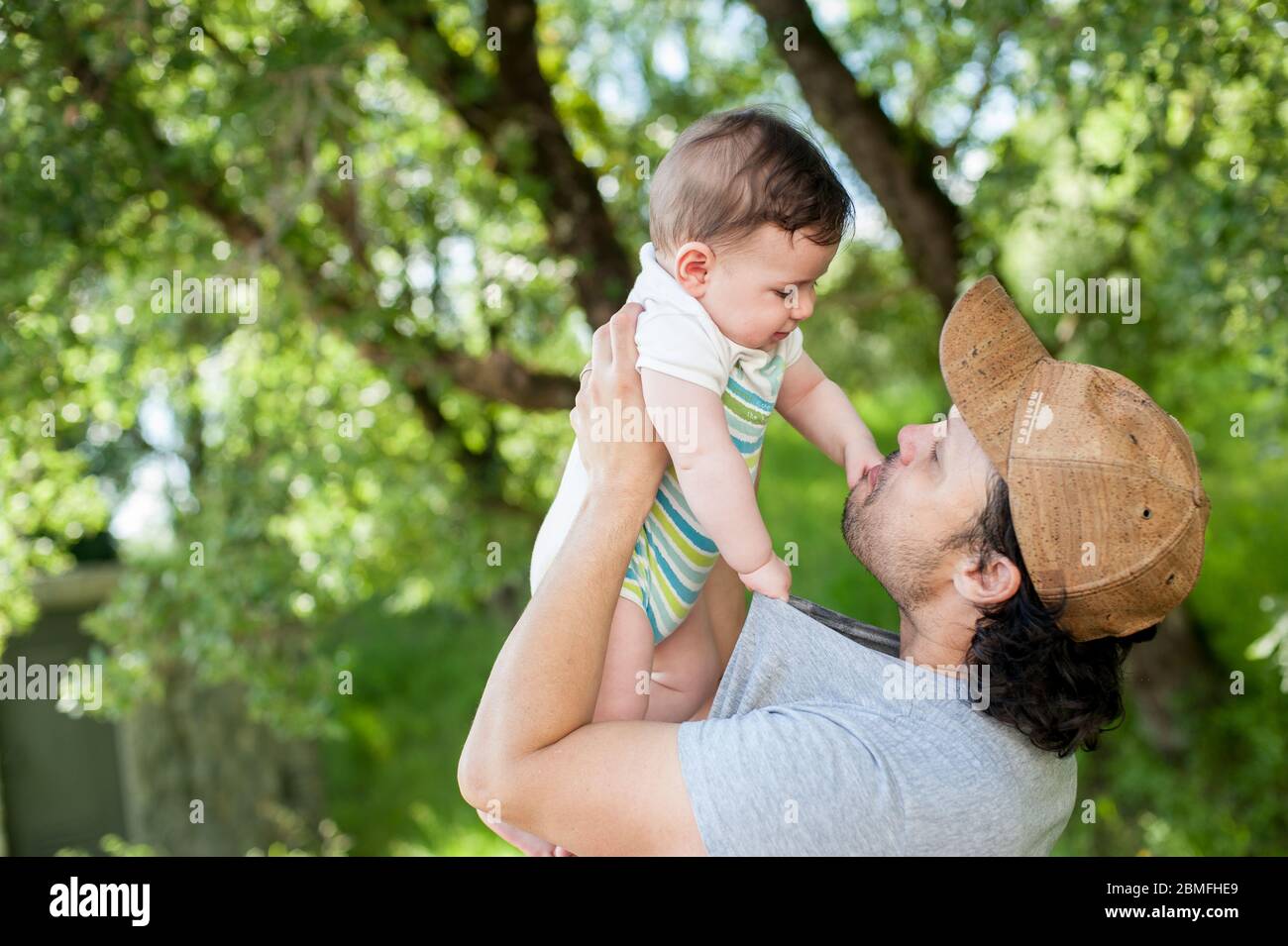 Profilansicht eines jungen Vaters, der mit seinem kleinen Jungen im Park spielt. Stockfoto