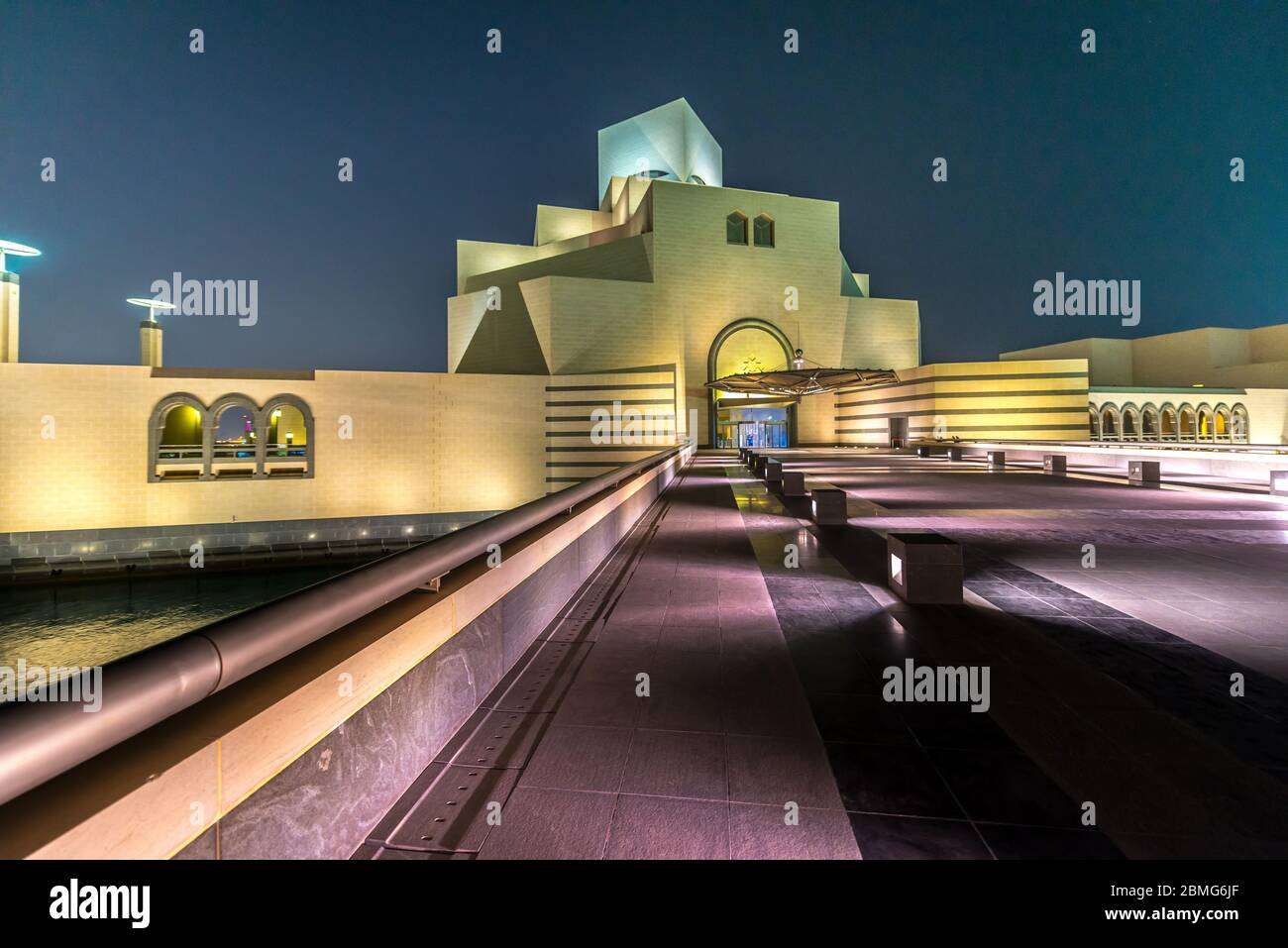 Besuch des Qatar Museum of Islamic Art in Doha Spiegelung in Wasser des Teiches in der Nacht. Futuristische Architektur in der Nähe der Bucht von Doha. Stockfoto