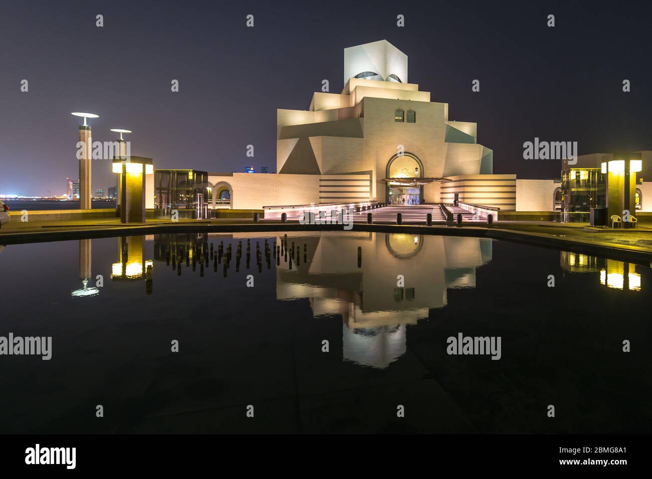 Besuch des Qatar Museum of Islamic Art in Doha Spiegelung in Wasser des Teiches in der Nacht. Futuristische Architektur in der Nähe der Bucht von Doha. Stockfoto