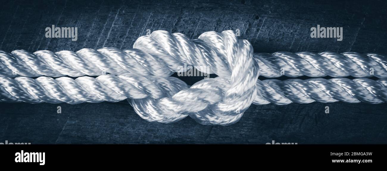 Nahaufnahme des weißen Seils, das auf dem hölzernen Schiffsdeck miteinander verbunden ist - Stärke im Partnerschaftskonzept Stockfoto