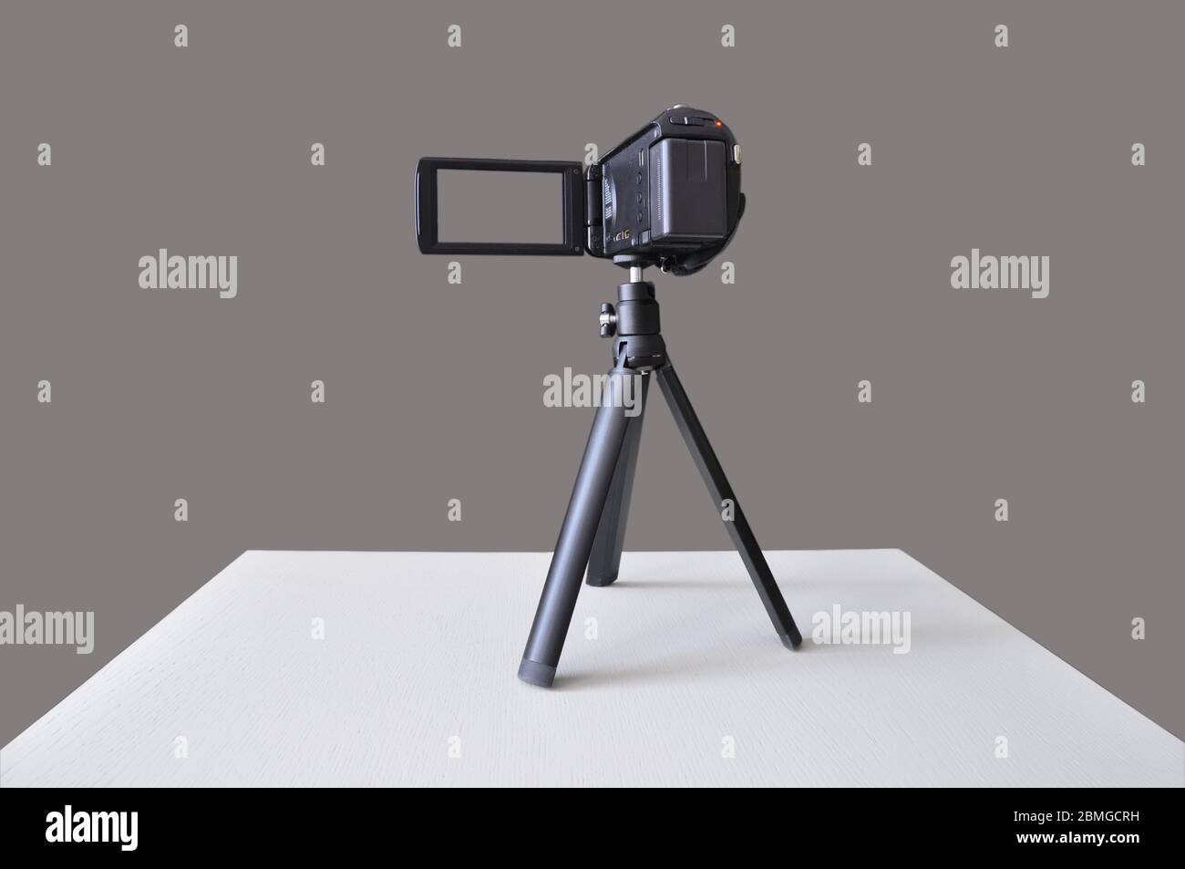 Digitale Videokamera auf einem Stativ isoliert auf einem grauen Hintergrund. Leer für Designer. Stockfoto