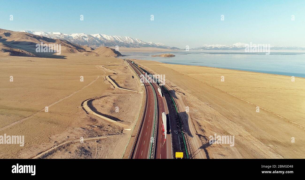 (200509) -- NUR-SULTAN, 9. Mai 2020 (Xinhua) -- Foto vom 24. April 2020 zeigt Lastwagen mit Windturbinenschaufeln entlang des Sayram-Sees im Nordwesten Chinas, der autonomen Region Xinjiang Uygur. Ende April schlenften drei Lastwagen mit silbernen Windkraftanlagen, die mehr als einen halben Fußballplatz lang waren, durch das Tal des Ili-Flusses im Nordwesten Chinas, der autonomen Region Xinjiang Uygur. Sie passten durch das Sayram-Seeufer und im Zickzack im Tianshan-Gebirge und fuhren zum China-kasachischen Grenzhafen Horgos. Die Lastwagen fuhren von Tianjin ab und transportierten Stockfoto