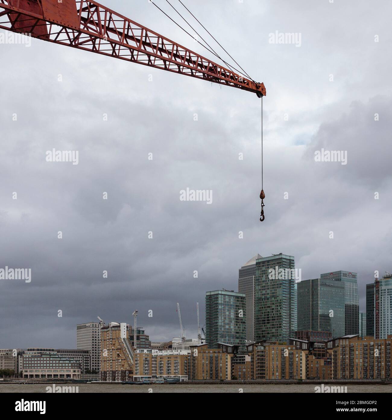 Die erzwungene Perspektive lässt einen Kran gigantisch über Canary Wharf erscheinen, von der anderen Seite der themse, London, England Stockfoto