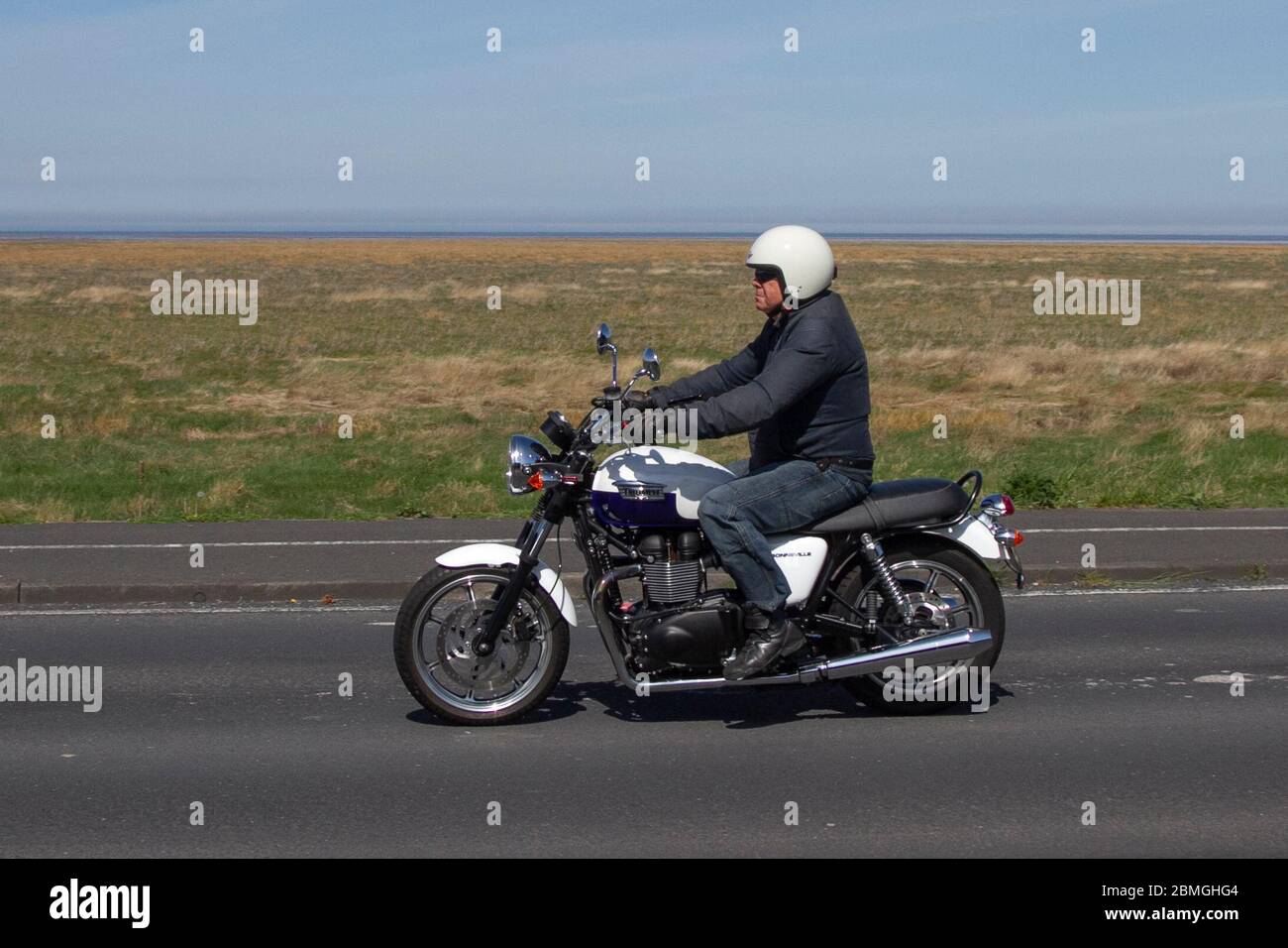 Triumph Bonneville T100; Motorradfahrer; Zweiradtransport, Motorräder, Fahrzeug, Straßen, Motorräder, Motorradfahrer, die auf der Küstenstraße in Southport, Großbritannien fahren Stockfoto