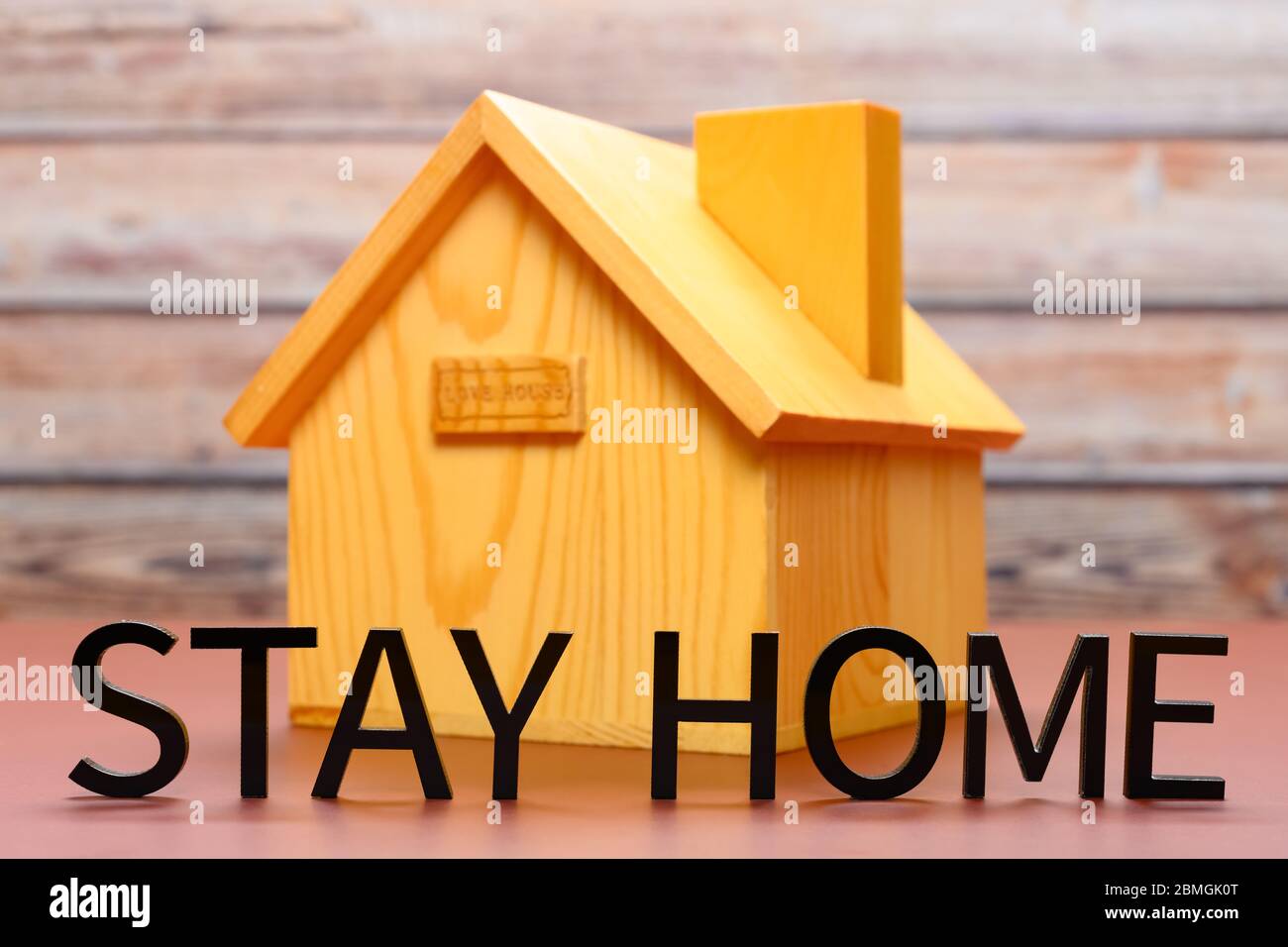 Worte des Aufenthalts zu Hause mit einem Haus Modell auf der Rückseite Stockfoto