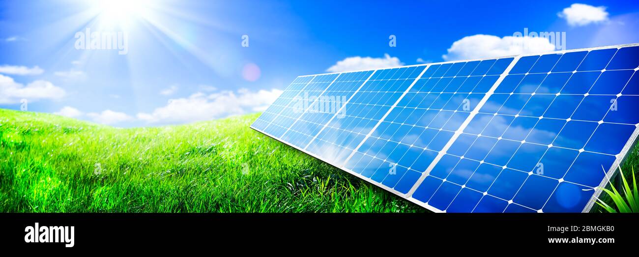 Solarpanels In Green Grass Landscape Mit Blauem Himmel Und Sonnenlicht - Clean Energy Concept Stockfoto