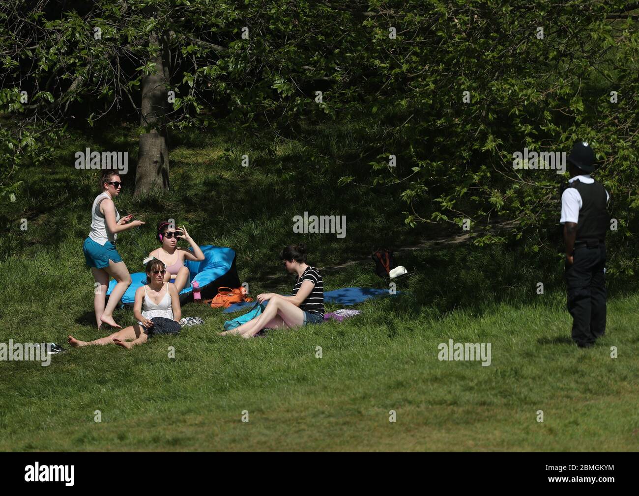 Ein Polizist zieht Sonnenanbeter in Greenwich Park, London, um die Ausbreitung des Coronavirus zu verhindern, während Großbritannien weiterhin gesperrt wird. Stockfoto