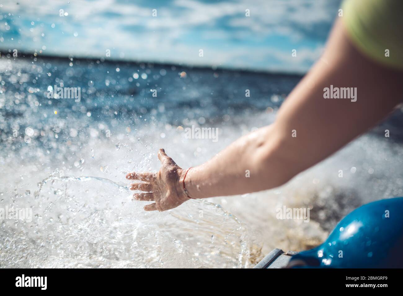 Die Hand einer Frau berührt das Spray auf einer schnellen Bewegung Boot auf den Wellen eines Sees oder des Meeres Stockfoto