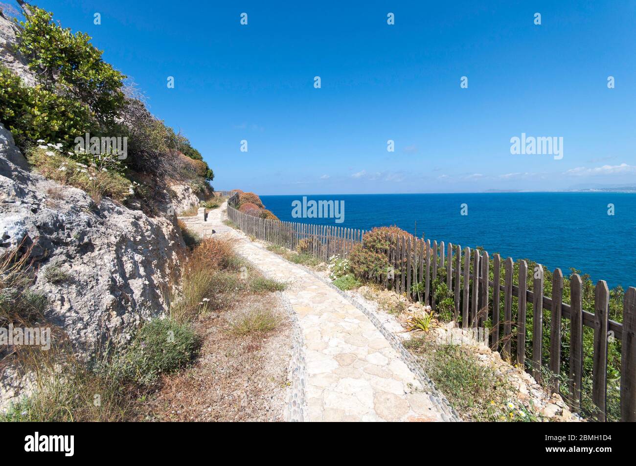 Klippenweg um Kolymvaria, Griechenland. Der schmale Pfad schlängelt sich entlang der steilen Klippen. Ein Tor erlaubt dem Wanderer eine kleine Kapelle zu erreichen. Stockfoto