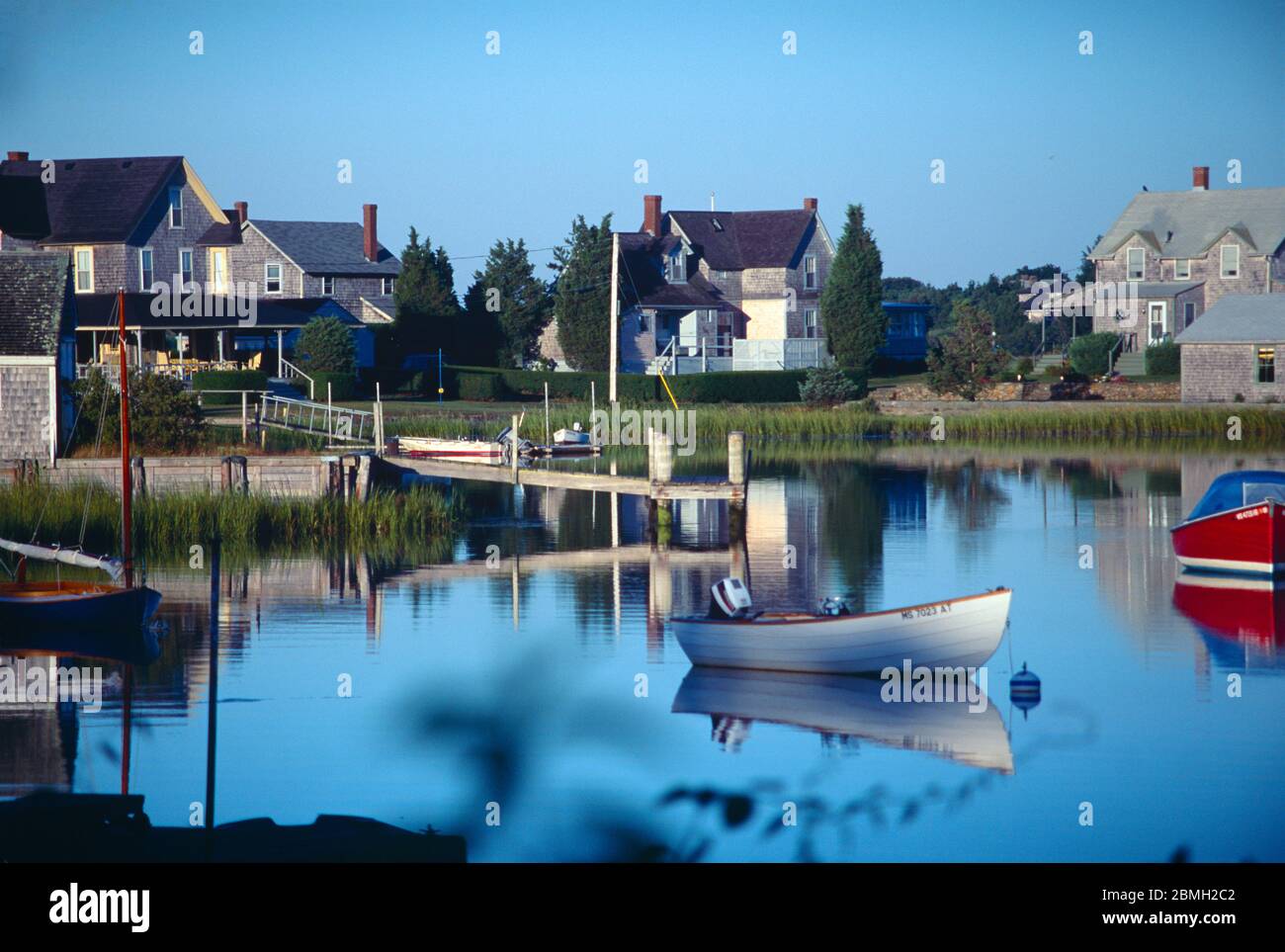 Ein Sommermorgen auf Snug Harbor in West Falmouth, MA. Die Reflexionen auf dem Wasser und den Hafenhütten schaffen eine friedliche Cape Cod Erinnerung. Stockfoto