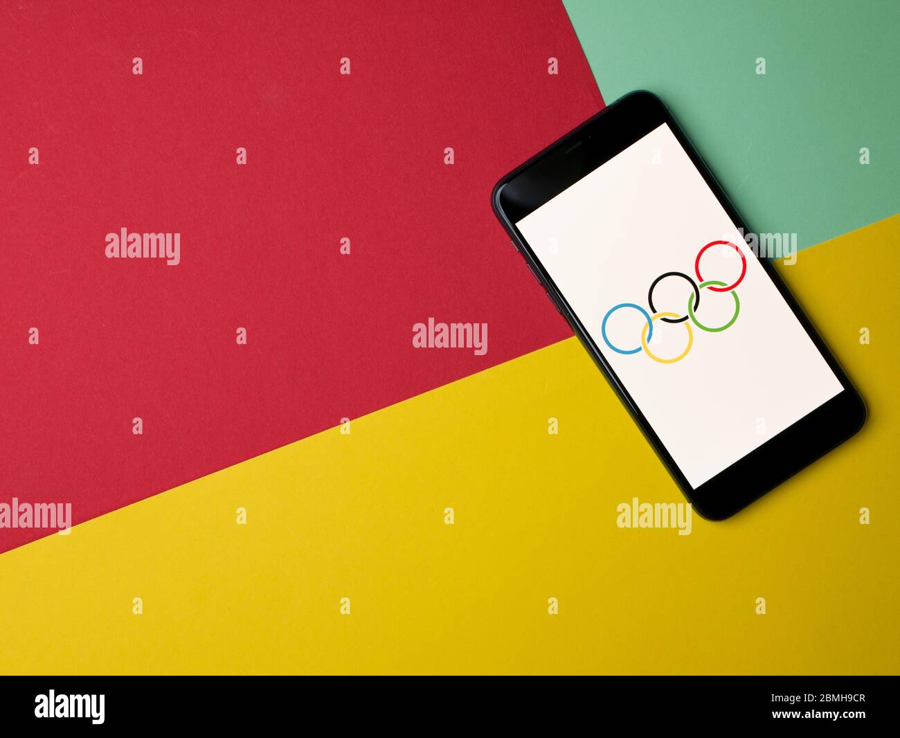 USA - Mai 2020 Olympic Games Logo auf iPhone-Bildschirm auf farbigem Papierhintergrund. Stockfoto