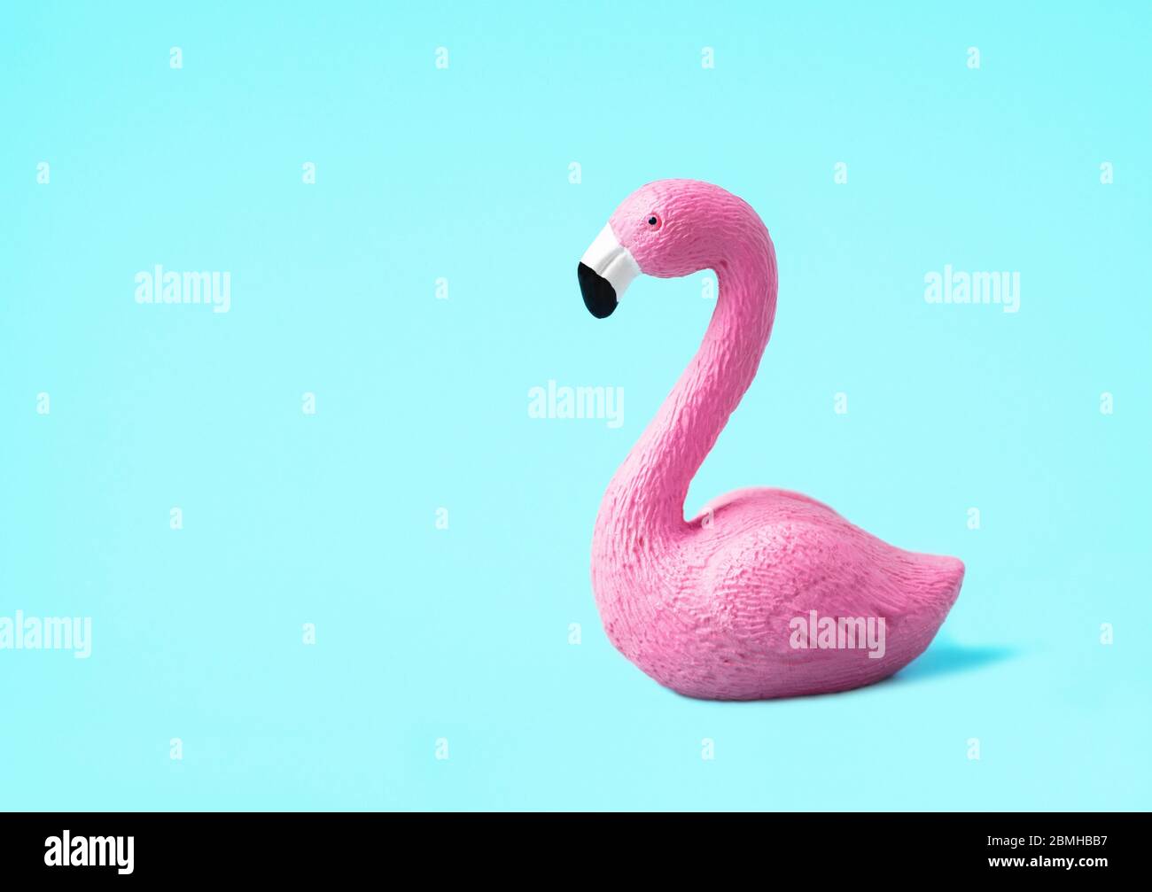 Nahaufnahme eines kleinen rosa Spielzeug Flamingo isoliert auf einem hellblauen Hintergrund. Sommerurlaub Konzept. Niedriger Winkel, Seitenansicht. Stockfoto