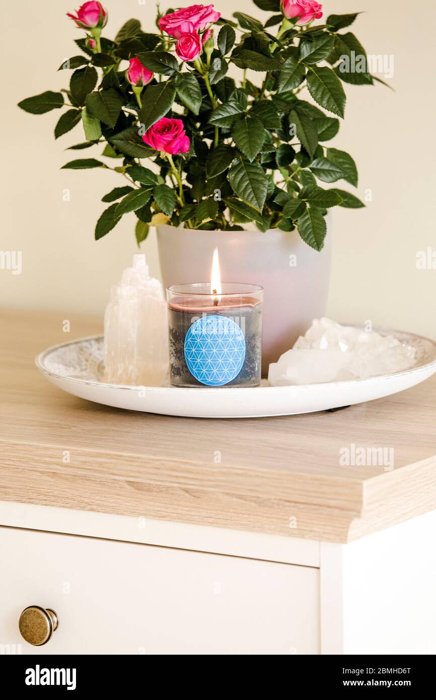 Brennende Glaskerze mit selbstgemachtem Schild, das das Symbol Blume des Lebens im Inneren mit Halbedelstein-Geoden zeigt. Spirituelle Symbole zu Hause. Stockfoto