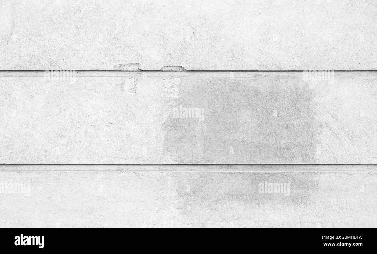 Verputzte und beschädigte graue Steinwand mit Flecken von Graffiti Entfernung. Abstrakter hochauflösender Vollformat-Hintergrund in Schwarz-Weiß. Stockfoto