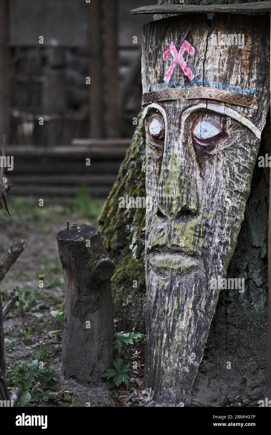 Große Holzmaske in der Nähe des Baumes. Stockfoto