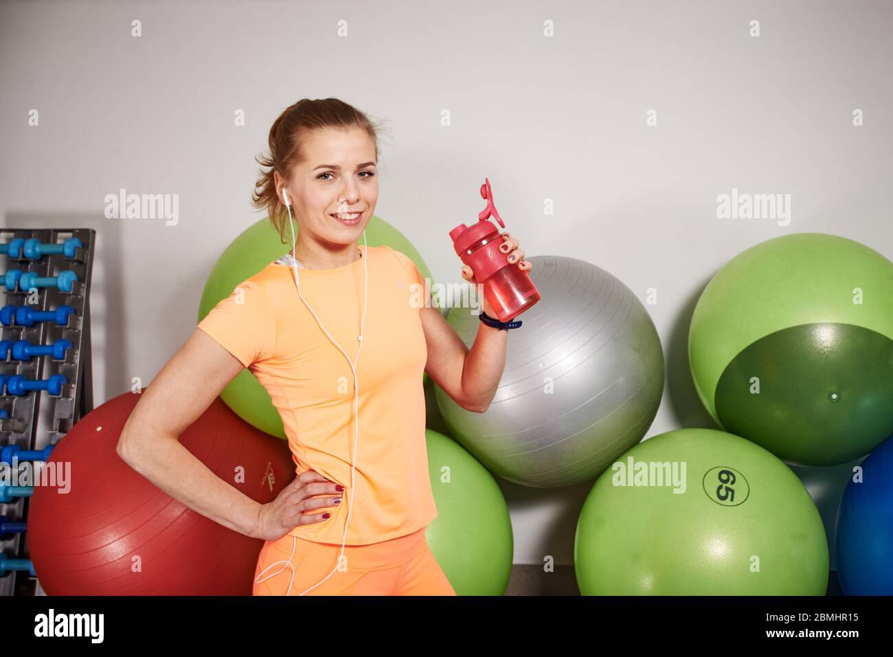 Schlanke sportliche junge Frau in Sportbekleidung mit Wasserflasche im Fitnessclub. Stockfoto