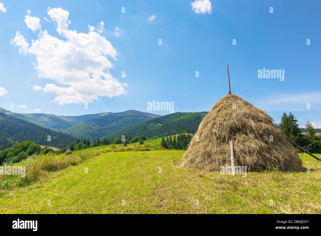 Idyllische ländliche Landschaft an einem sonnigen Sommertag. Idyllische ländliche. Heuhaufen auf dem Feld. Herrliche Landschaft in Bergen unter blauem Himmel mit Flusen Stockfoto