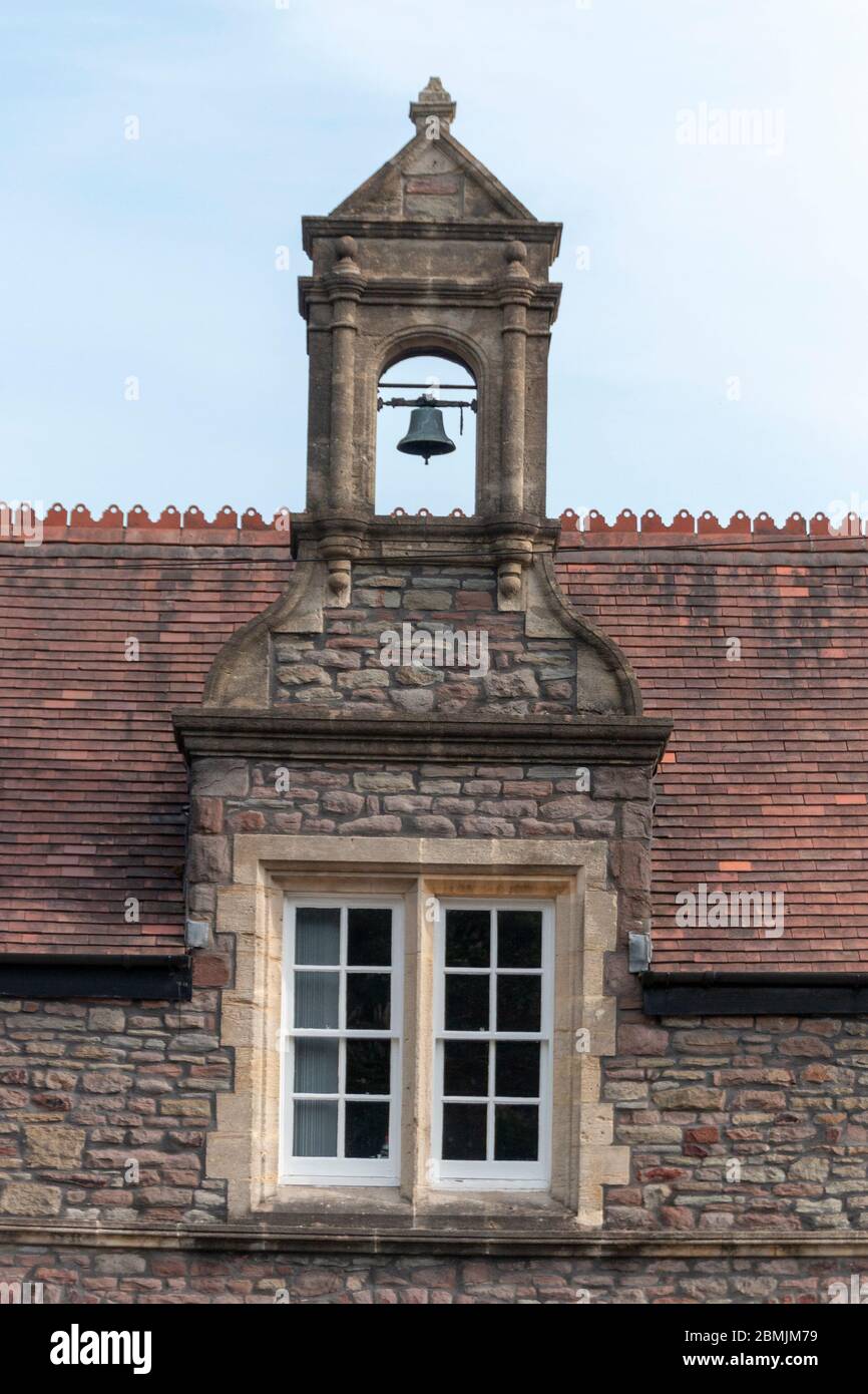 Bristol-May-2020-England- eine Nahaufnahme einer Glocke über einem kleinen Kirchenfenster Stockfoto