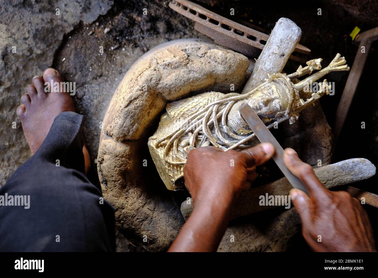 Handwerker, die die letzten Details einer Bronzestatuette polieren, die mit der Technik des Wachsausschmelzens hergestellt wurde, die im Königreich von Be verwendet wurde Stockfoto