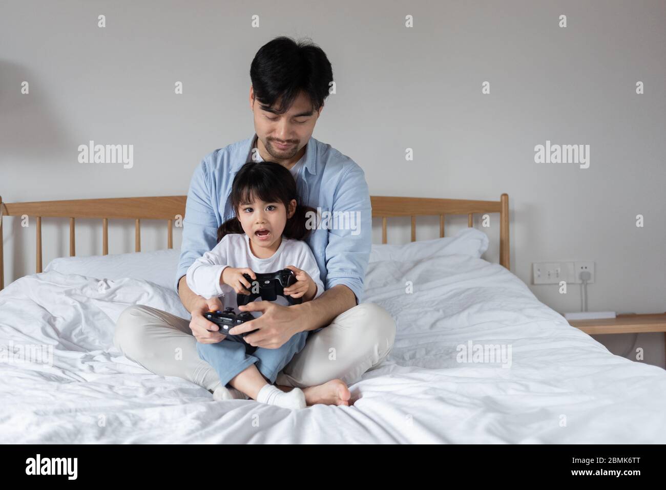 Junge asiatische Vater ist spielen Spiele auf dem Bett mit Tochter  Stockfotografie - Alamy