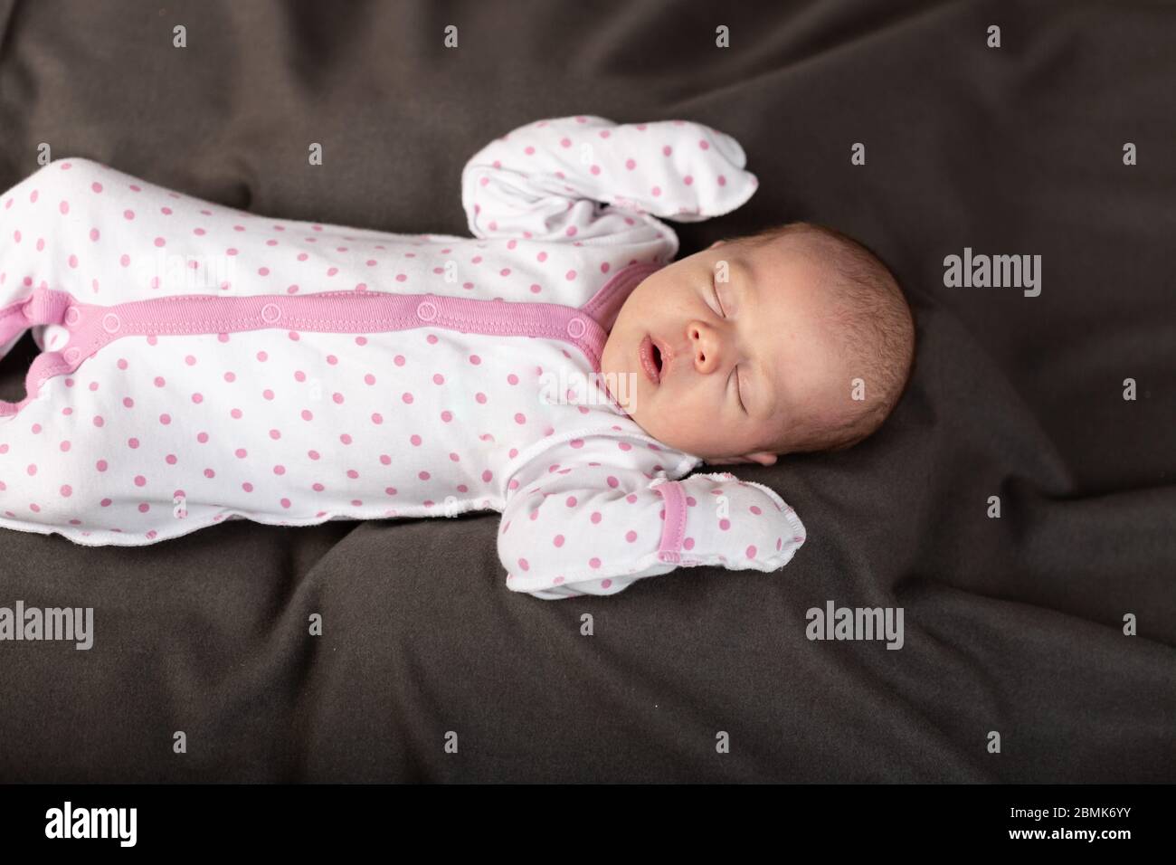 Kleiner neugeborener Junge schläft im dunklen Hintergrund Stockfoto