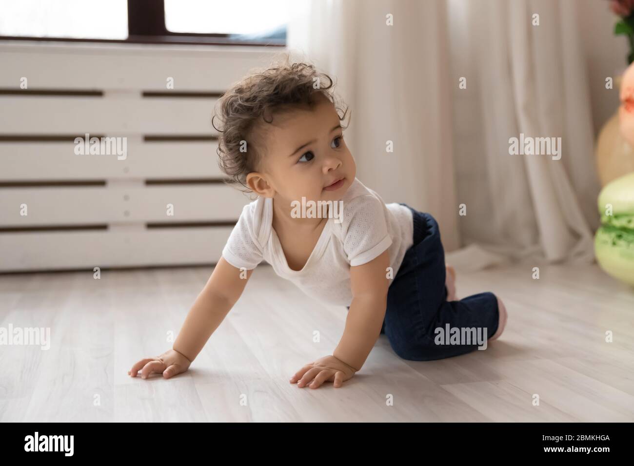 Kleines biracial Baby kriechen auf Vieren zu Hause Stockfoto
