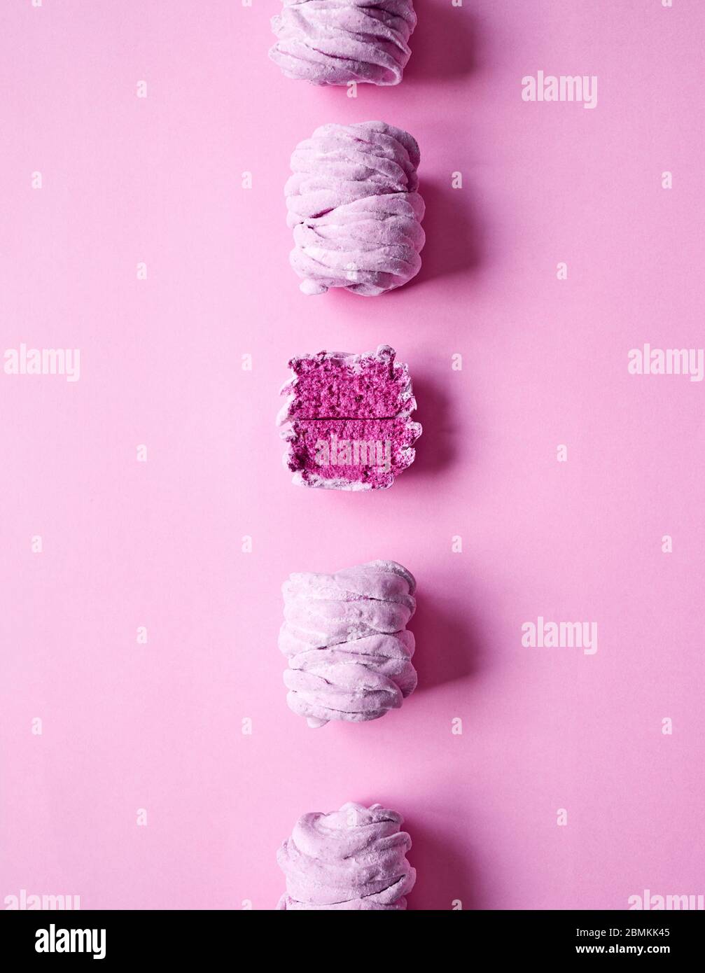 Linie von Violet süß hausgemachte Zephyr oder Marshmallow aus schwarzer Johannisbeere auf rosa hellen Hintergrund. Ein zephyr wird geschnitten. Draufsicht Stockfoto