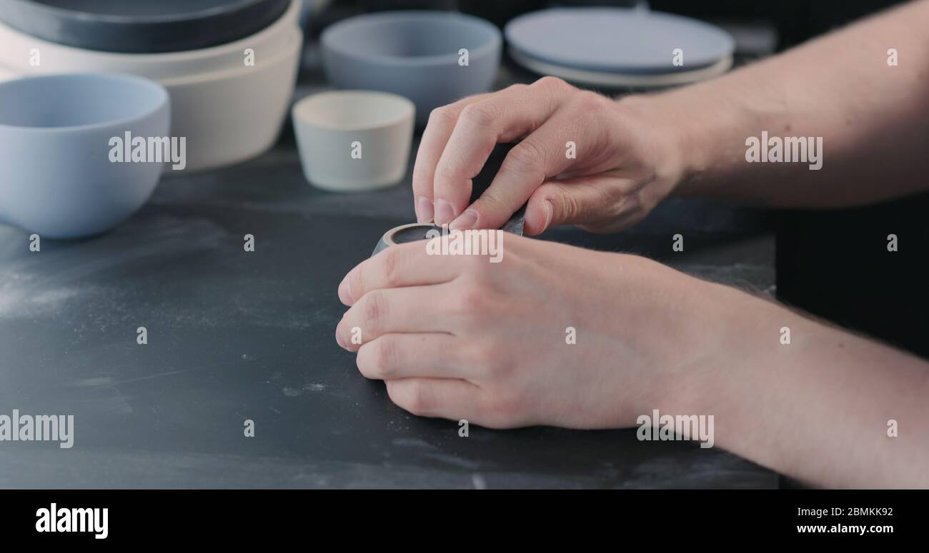 Mann Hände Polieren unten aus schwarzer Keramik Tasse Stockfoto