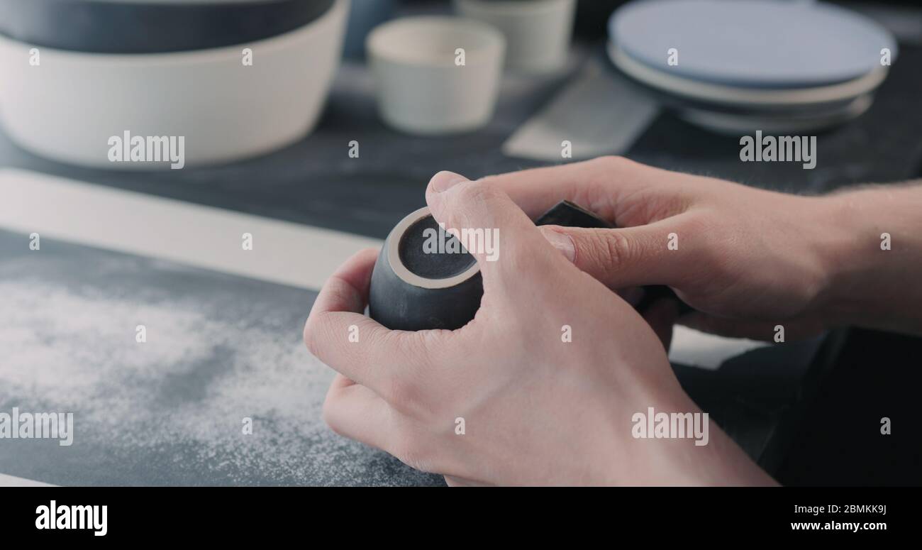 Mann Hände Polieren unten aus schwarzer Keramik Tasse Stockfoto