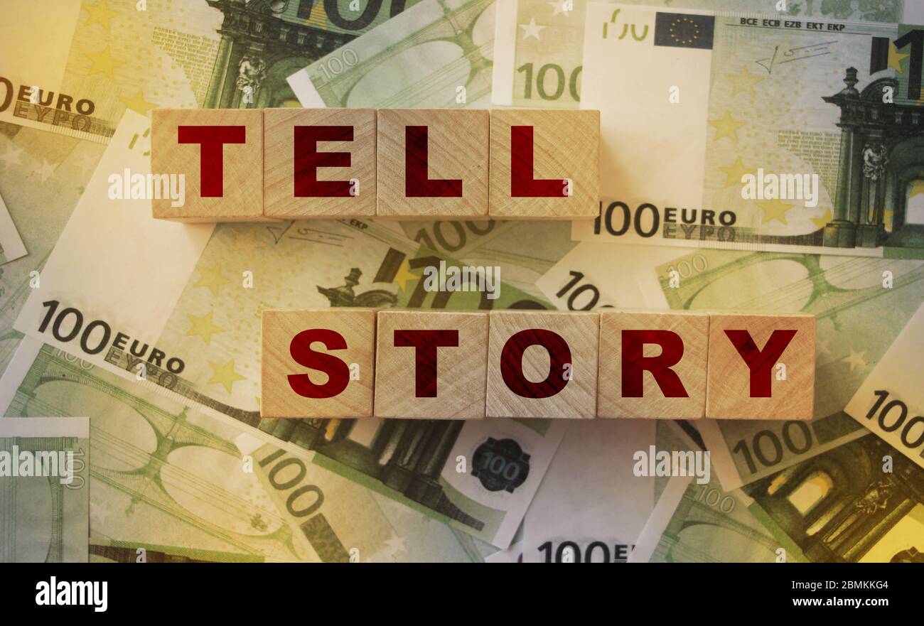 Holzblöcke mit dem Text: Tell Story auf 100 Euro-Banknoten. Copywriting Storytelling Marketing-Konzept Stockfoto