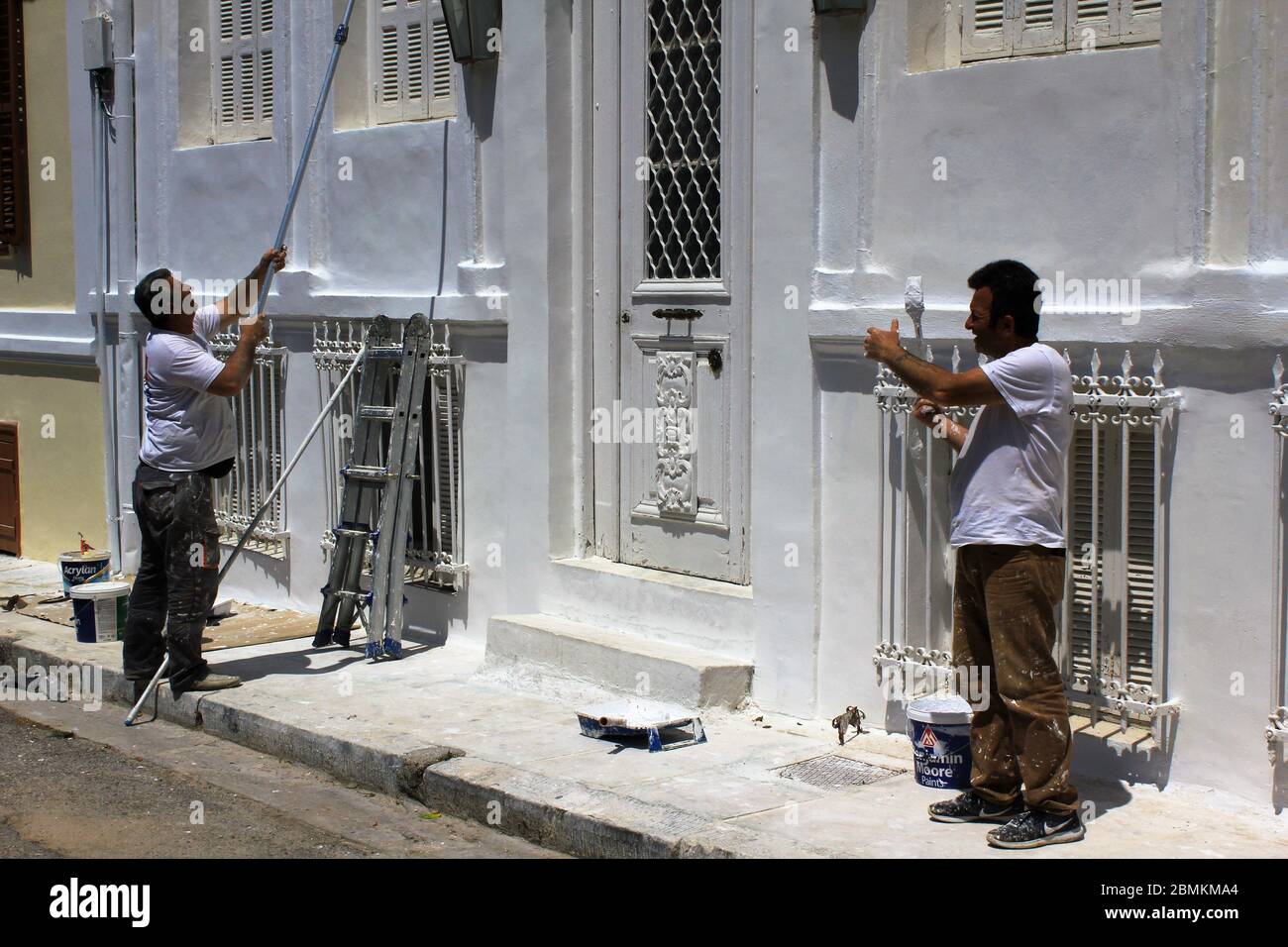 Männer bei der Arbeit, die Außenwand eines Hauses in Weiß malen - Athen, Griechenland, 6. Mai 2020. Stockfoto