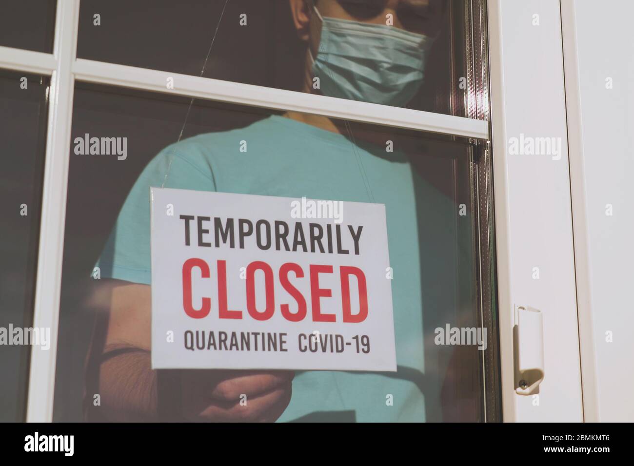 Unternehmer in der medizinischen Maske setzt ein GESCHLOSSENES Zeichen Stockfoto