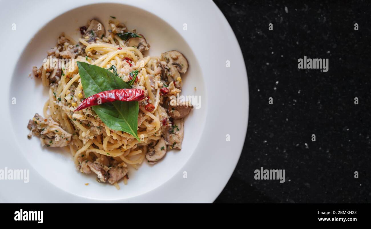 Spaghetti mit gesalzenem Fisch, thailändischen Gewürzen und trockenem Chili in weißer Schüssel anbraten Stockfoto