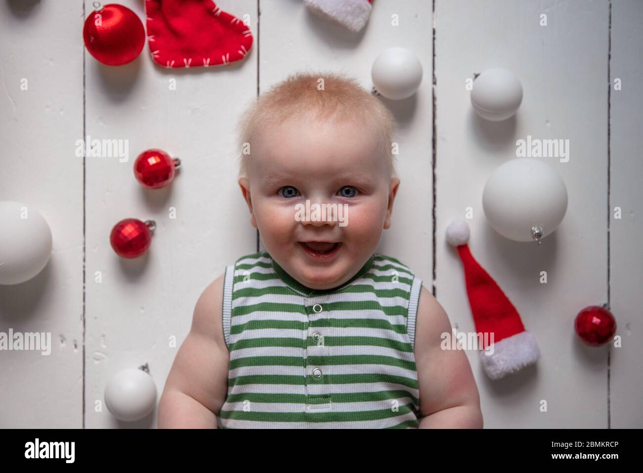 Fröhliches Baby umgeben von festlichen Dekorationen, die Weihnachten feiern Stockfoto