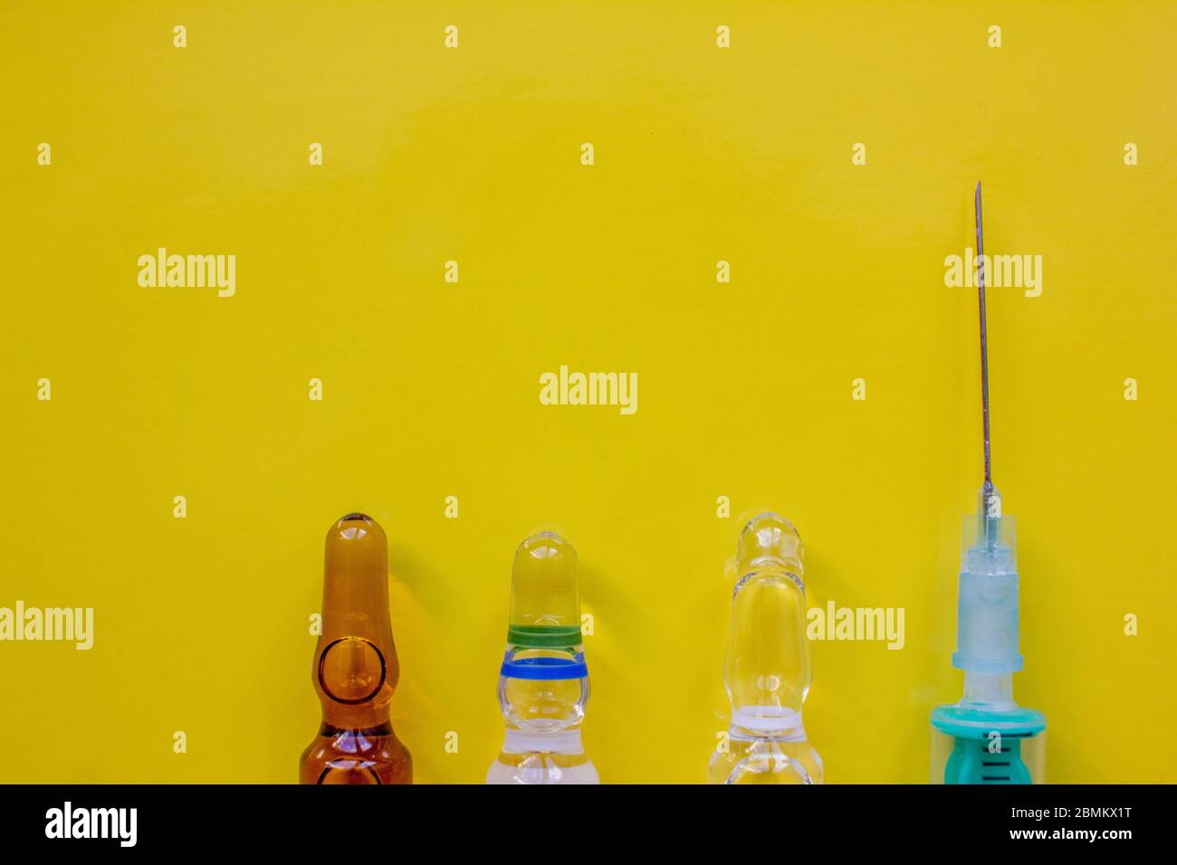Eine Spritze mit einer Nadel und Ampulle mit Medikamenten auf gelbem Hintergrund. Impfkonzept Stockfoto
