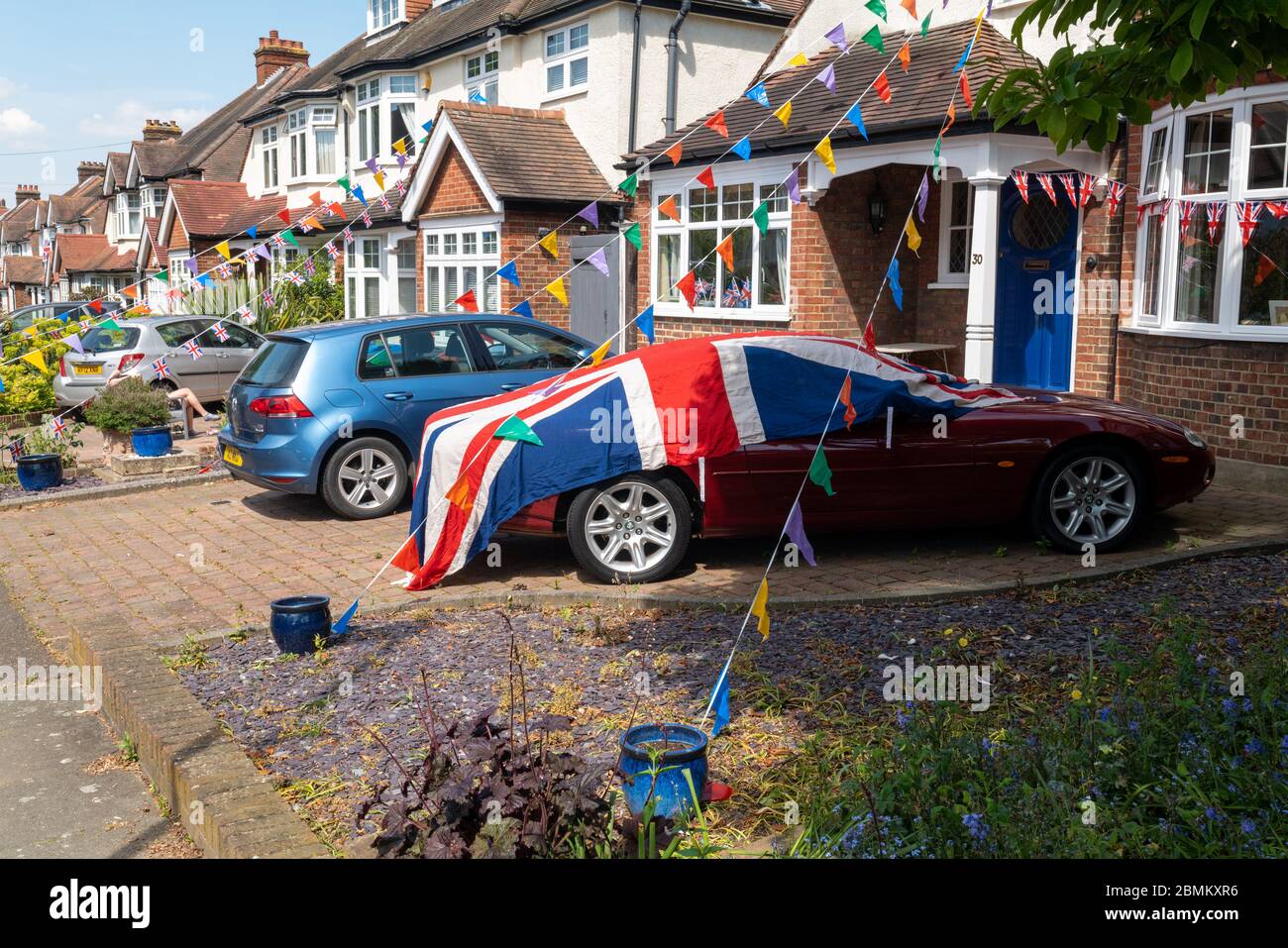 Eine Straße in einem Londoner Südwesten, bekleidet mit einer Ammer und einer großen Union-Flagge, die über einem Jaguar-Auto zum VE-Tag drapiert war. Stockfoto