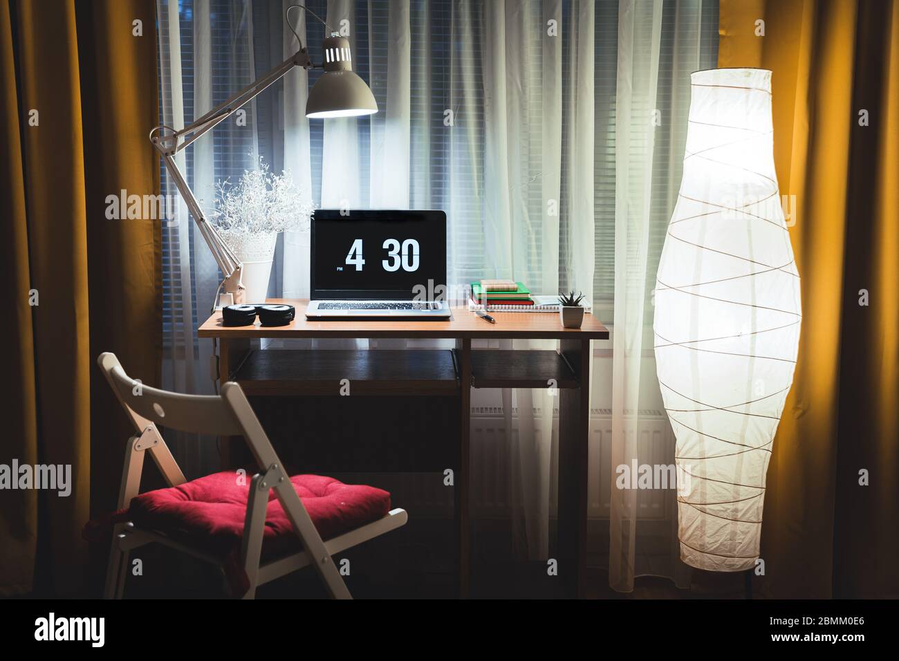 Moderne Abendinterieur des Wohnzimmers mit kleinem Schreibtisch und  Stehlampe gegen Fenster. Laptop auf dem Tisch bereit, spät in der Nacht  Arbeit Überstunden zu beginnen Stockfotografie - Alamy