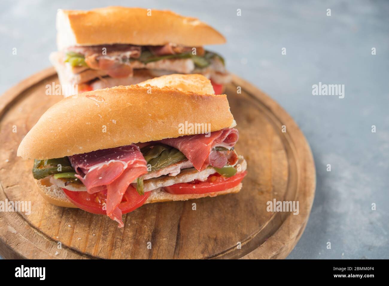Sandwich Serranito typisch in Andalusien mit Schinken, gren Pfeffer und gegrilltem Schweinefleisch Lende Stockfoto