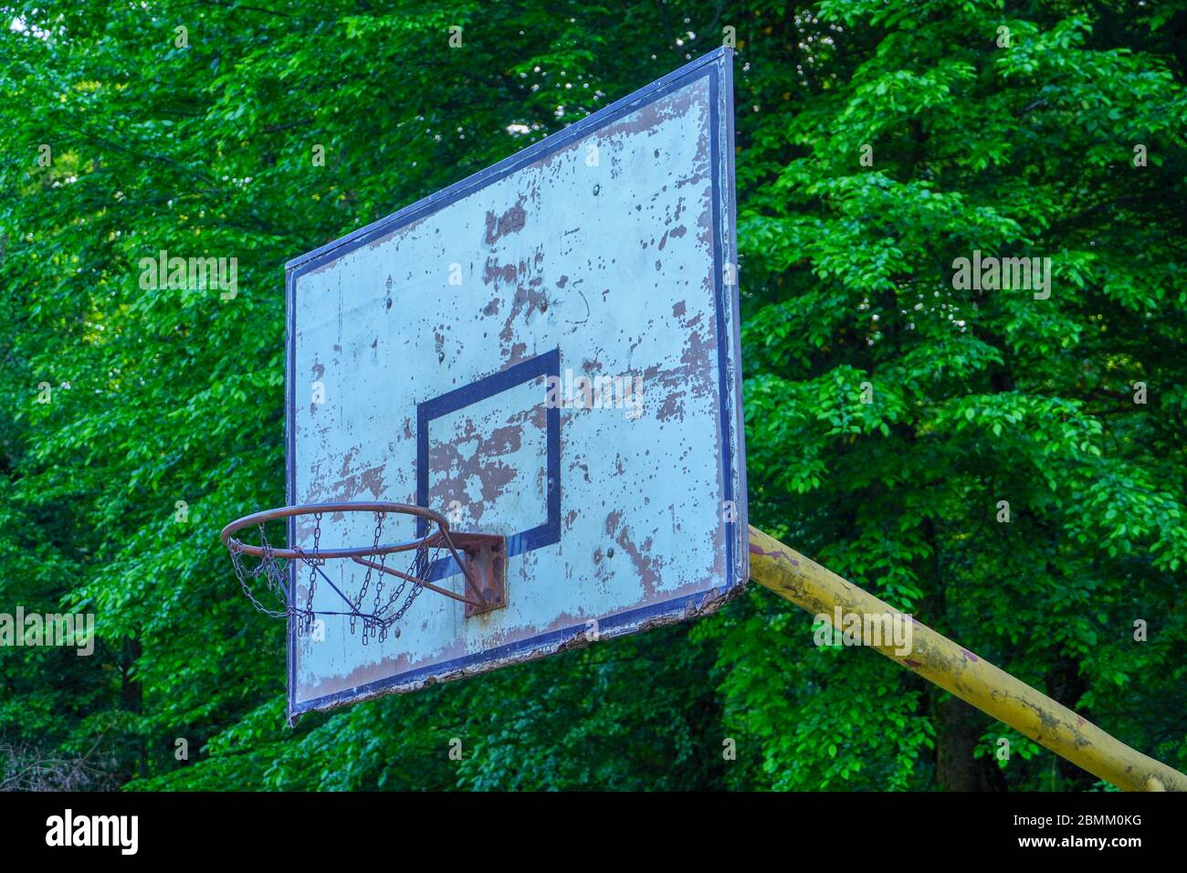 Alter Basketballkorb im Park mit grünen Bäumen als Hintergrund. Stockfoto