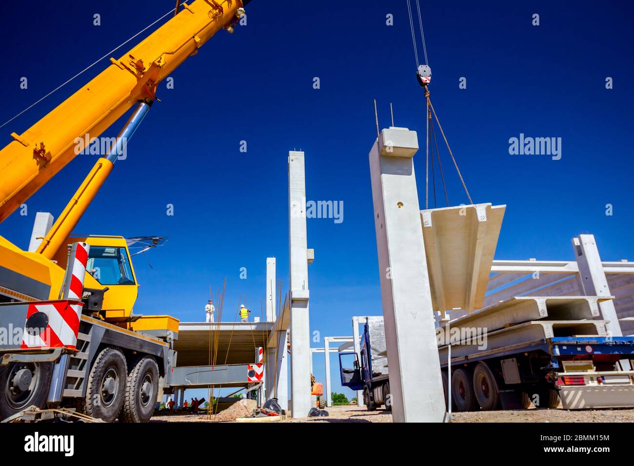 Lkw-anhänger ist beim Entladen Cargo, konkreten Balken für die Montage von Beton edifice, Baustelle. Stockfoto