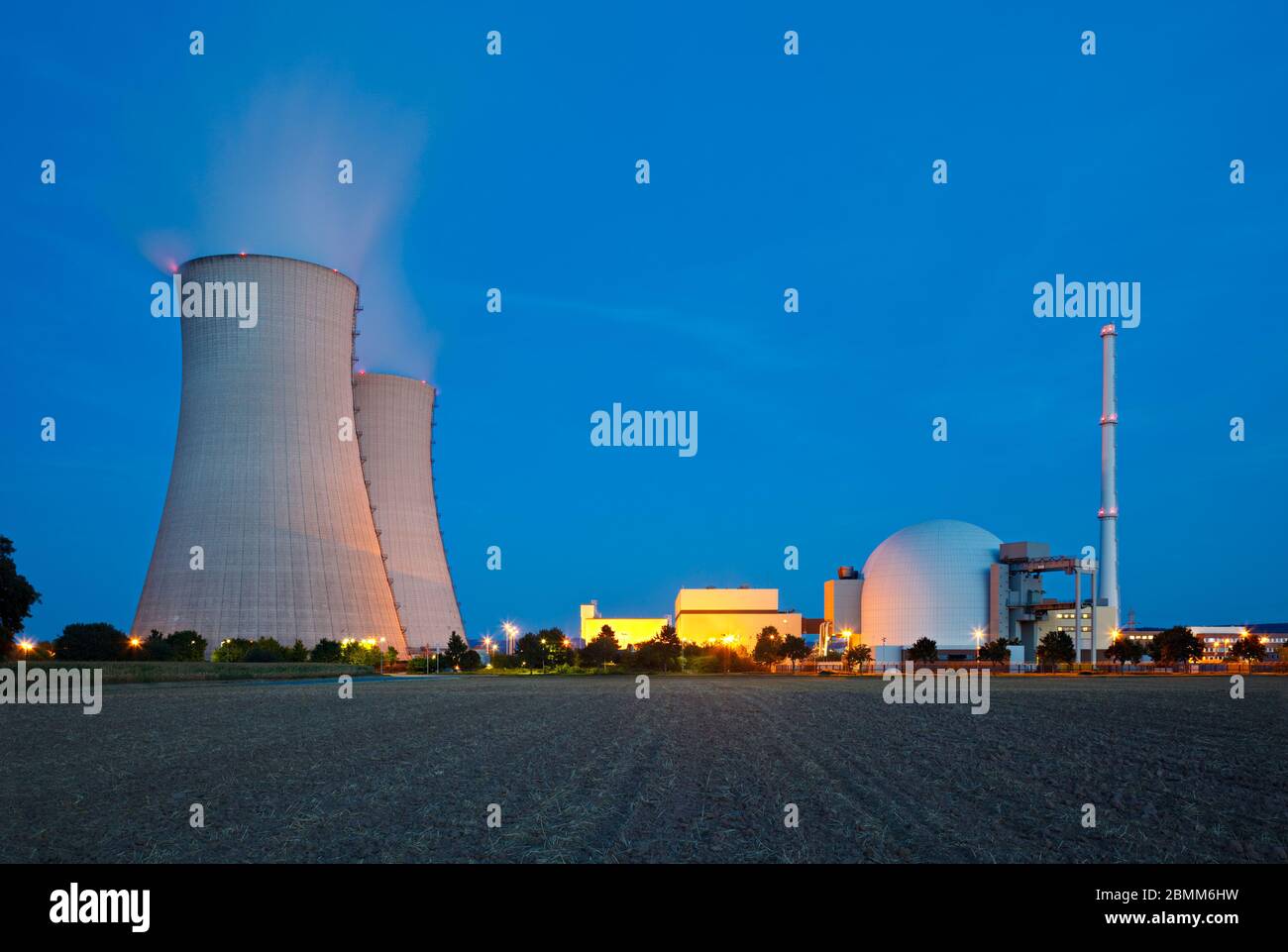 Ein Kernkraftwerk mit nächtlichen blauen Himmel, ein Feld im Vordergrund. Stockfoto